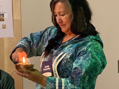 Jackie Qatalina Schaeffer lights a seal oil lamp in Nome, Alaska. October 2022.